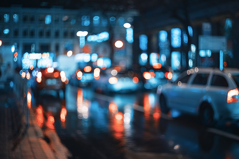 朦胧的城市在夜晚。散景。美丽的抽象场景与散焦的建筑，汽车，城市灯光，人。丰富多彩的散景背景与城市夜景