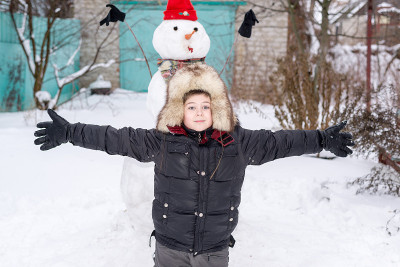 那个戴毛帽子的男孩围着雪人