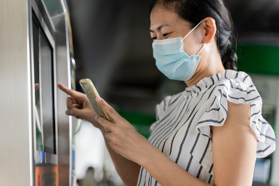 戴口罩的女子在自动售票机购买地铁车票