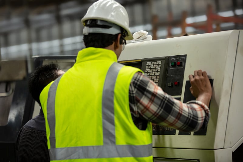 Engineers operating a cnc machine in factory