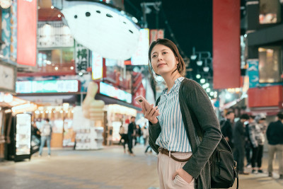 一位女士站在tsutenkaku的temming街上