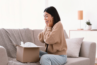 兴奋的亚洲女士打开包裹后网上购物