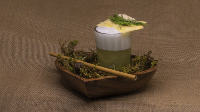 特写签名私酿鸡尾酒与竹稻草和苔藓在麻袋布背景。酒精的概念。