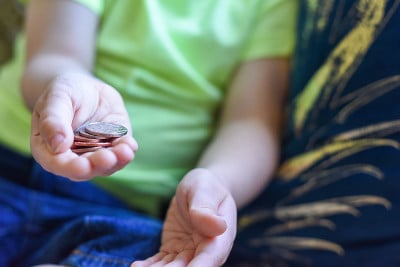 孩子手里拿着钱，现金是英国货币硬币