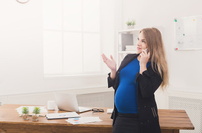 怀孕的女商人在办公室打电话
