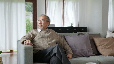 亚洲老年人老年男性或抑郁的爷爷在养老院的起居室对隔离看窗外，感觉悲伤思念不快乐周到的心理保健老年人。
