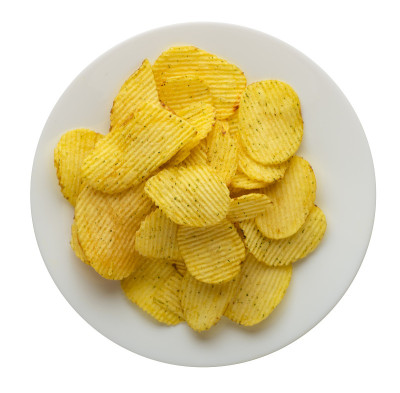 土豆片放在盘子里。在白色背景上孤立的薯片。垃圾食品