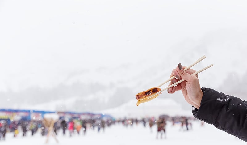 在冰雪节手握筷子烤鱿鱼