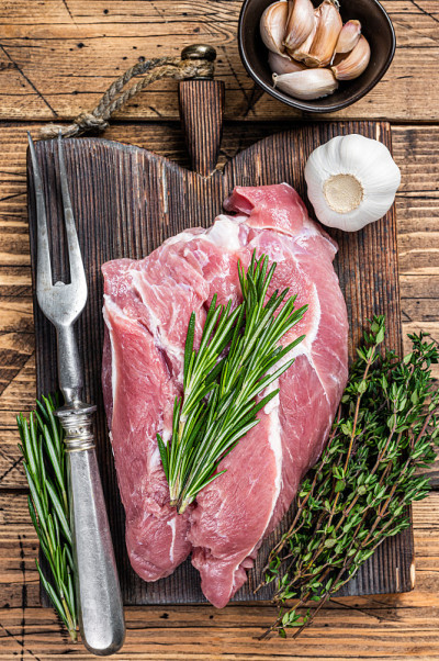 新鲜的生猪肉肩肉，配料和香料放在木制砧板上。木制背景。俯视图