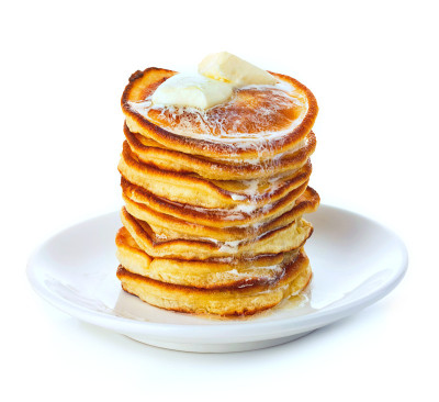 Stack of small pancakes in syrup on white backgrou