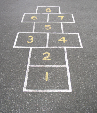 用粉笔在混凝土上画上黄色数字的跳房子