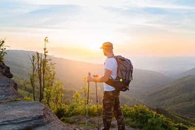 手持登山杆观看美丽日出的游客
