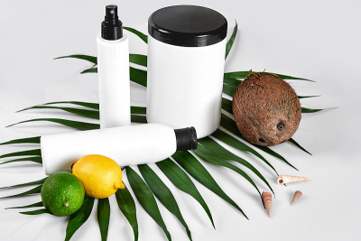 家用天然化妆品。俯视图瓶霜，洗发香波，精油面膜，新鲜酸橙果，绿叶装饰，白色背景