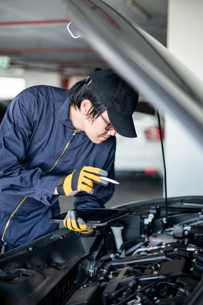 亚洲汽车技师用平板电脑检查汽车