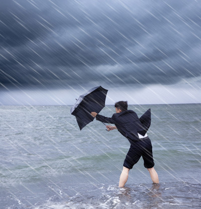拿着雨伞抵御暴风雨的商人