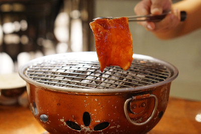 在热炭炉上烤生黑罗巴肉片。
