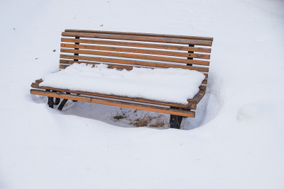 公园长椅被大雪覆盖。雪下寂寞的木凳。下雪的一天。完美的圣诞假期