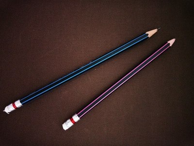 两支铅笔孤立在深棕色的布背景上