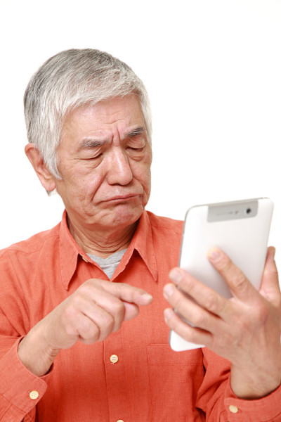 日本一名高级男子在用平板电脑，一脸困惑
