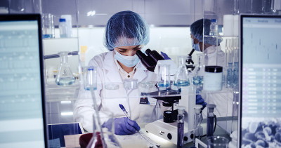 研究DNA突变的多种族女性团队。在防护服中使用显微镜