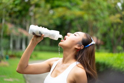 年轻的运动女孩喝着瓶子里的水