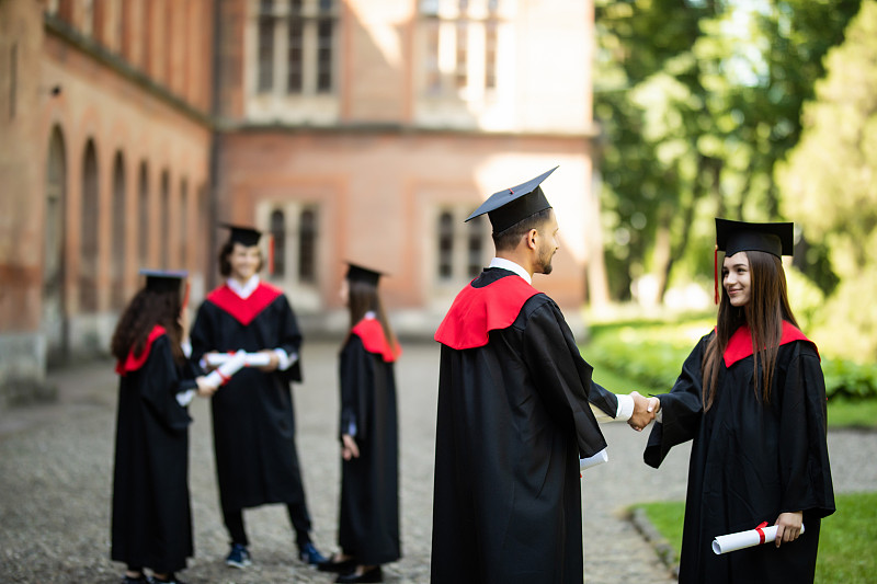 教育、毕业与人观念。一群快乐的国际学生在学位板和学士学位袍与文凭