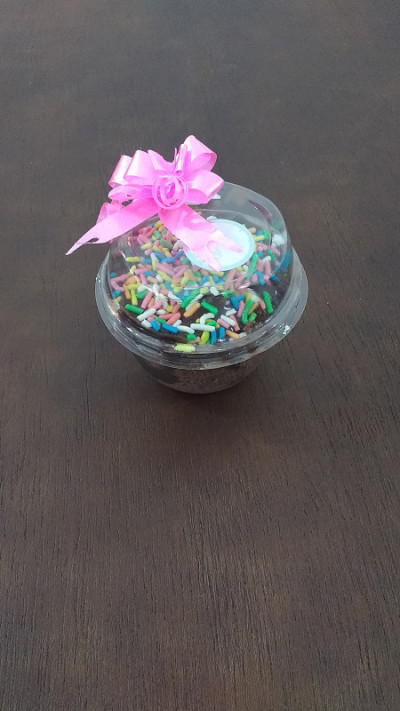 巧克力味的锅蛋糕，有彩色的点缀，盖子上有粉红色的蝴蝶结。