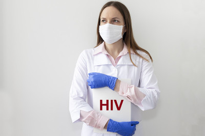 戴口罩的医生拿着一张印有HIV标志的纸