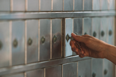 一个女人的手打开一个小钥匙信箱的特写-邮局信箱或邮政信箱概念-银行存款箱