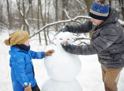 小男孩和他的父亲在下雪的公园堆雪人。冬季与孩子们一起活跃户外休闲活动。孩子在雪地里散步