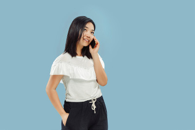 蓝色背景上的韩国年轻女子的半长肖像