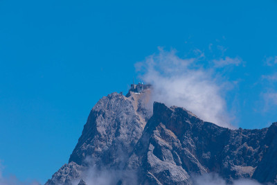 从蓬松的云雾中穿过Zugspitze的岩石山峰。文本。