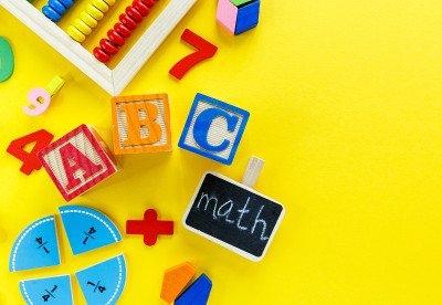 黄色背景上的彩色数学分数。桌子上有学校字样的街区。对孩子们来说，有趣的数学。教育，回归学校理念