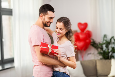 幸福的夫妇用礼盒在家拥抱