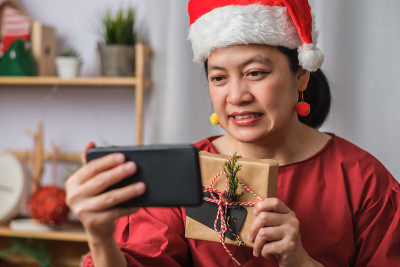亚洲妇女戴圣诞帽视频电话聚会与朋友与移动电话桌上在家里