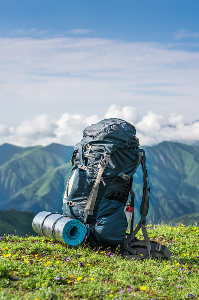 旅游背包和睡袋在山的背景