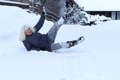 一个女人滑倒在一条被雪覆盖的路上