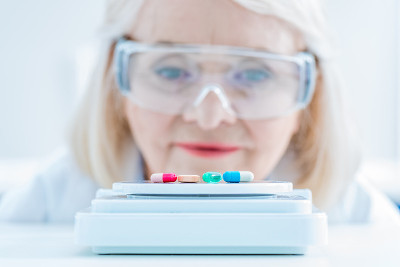 高级女科学家在实验室尺度上观察药片的肖像