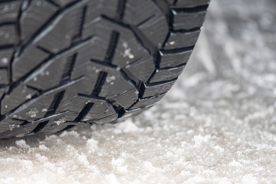 近距离观察一辆车在冰雪覆盖的道路上的冬季轮胎