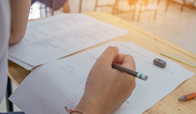 学生在高中、亚洲考场使用铅笔在白纸上写信息，测试或考试是评估的目的是衡量知识、技能、能力倾向、教育理