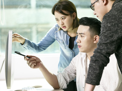 由三位年轻的亚洲企业家组成的团队正在办公室讨论业务