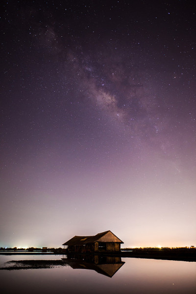 位于泰国南部的天空上的一条银河，在夜晚的时候房子前景在水面上的倒影