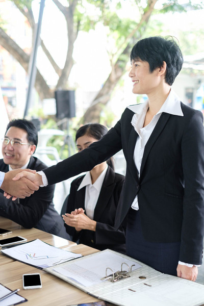 欢迎登机!亚洲商务人士与新合伙人握手会议时间后同意加入新启动项目，商务同事团队合作的理念
