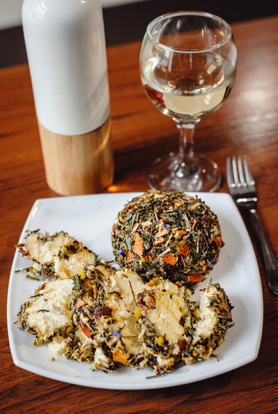 这是一个白色盘子，上面撒着法国香辣的Boulette d'Avesnes奶酪，上面撒着各种香草。布林