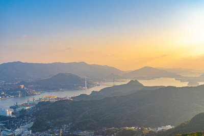 在阳光明媚的日子日落时分，从稻叶山观景台甲板上俯瞰长崎的城市全景