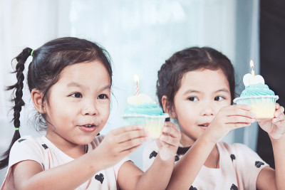 两个可爱的亚洲女孩玩吹生日蛋糕一起