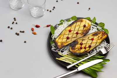 烤茄子配青菜和米粉在黑盘子里