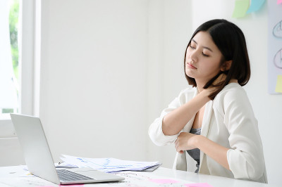 办公室综合症的概念。年轻的亚洲女商人在长时间使用电脑后感到脖子痛