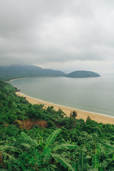 越南岘港海凡山口顺化的琅哥海滩全景。火车在海边的铁路上行驶，绿色的森林，美丽的自然景观，海浪