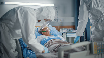 医院冠状病毒急诊科病房:医生、身穿工作服的医护人员、戴着口罩挽救一位躺在床上带氧气面罩的年长女性患者